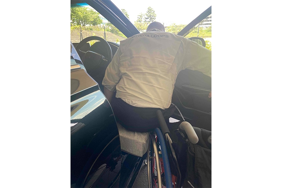車いすからクルマへ乗り込む様子 車いすとクルマ（シート）の隙間をクッションで埋める工夫をしている
