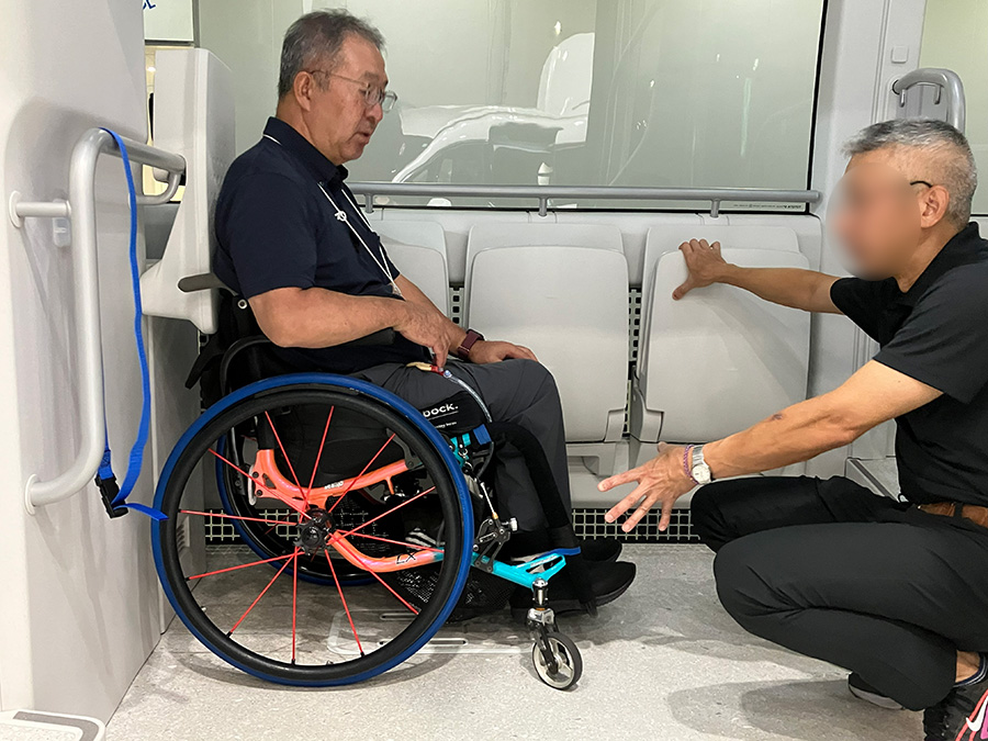 2025年のHCRで車いすワンタッチ固定装置の担当者に開発状況を確認する様子。自身が関わったプロジェクトが社会へ実装される未来が間近に迫り、喜びを噛みしめる