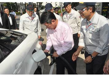 Toshimitsu Motegi, Japanese Minister of Economy, Trade and Industry (center), refuels Toyota's fuel cell sedan
