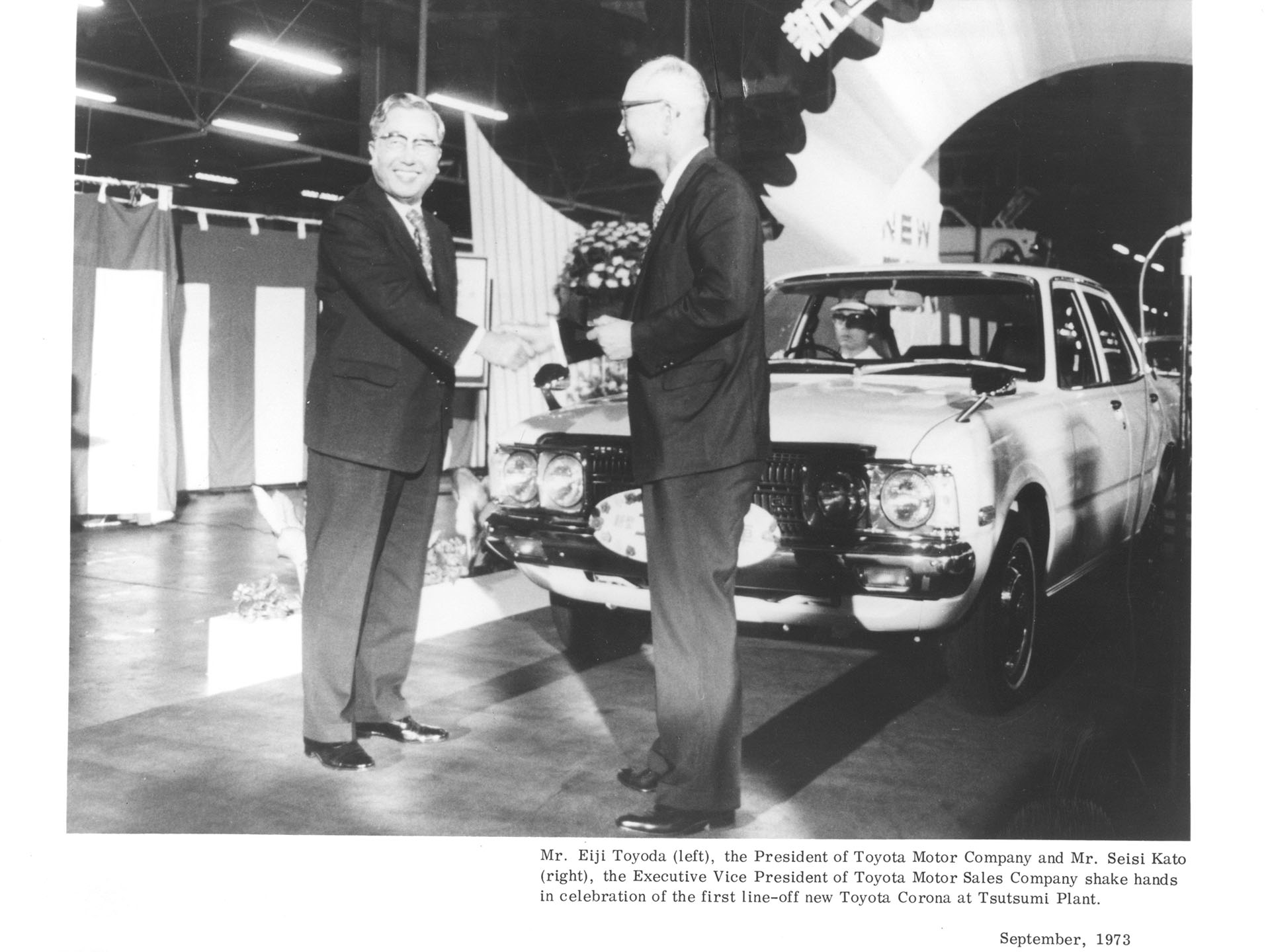 Mr. Eiji Toyoda (left), the President of Toyota Motor Company and Mr. Seisi Kato (right), the Executive Vice President of Toyota Motor Sales Company shake hands in celebration of the first line-off new Toyota Corona at Tsutsumi Plant.